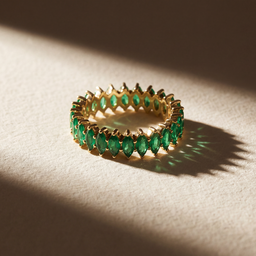 Gold ring with green emrald gemstones on a textured surface