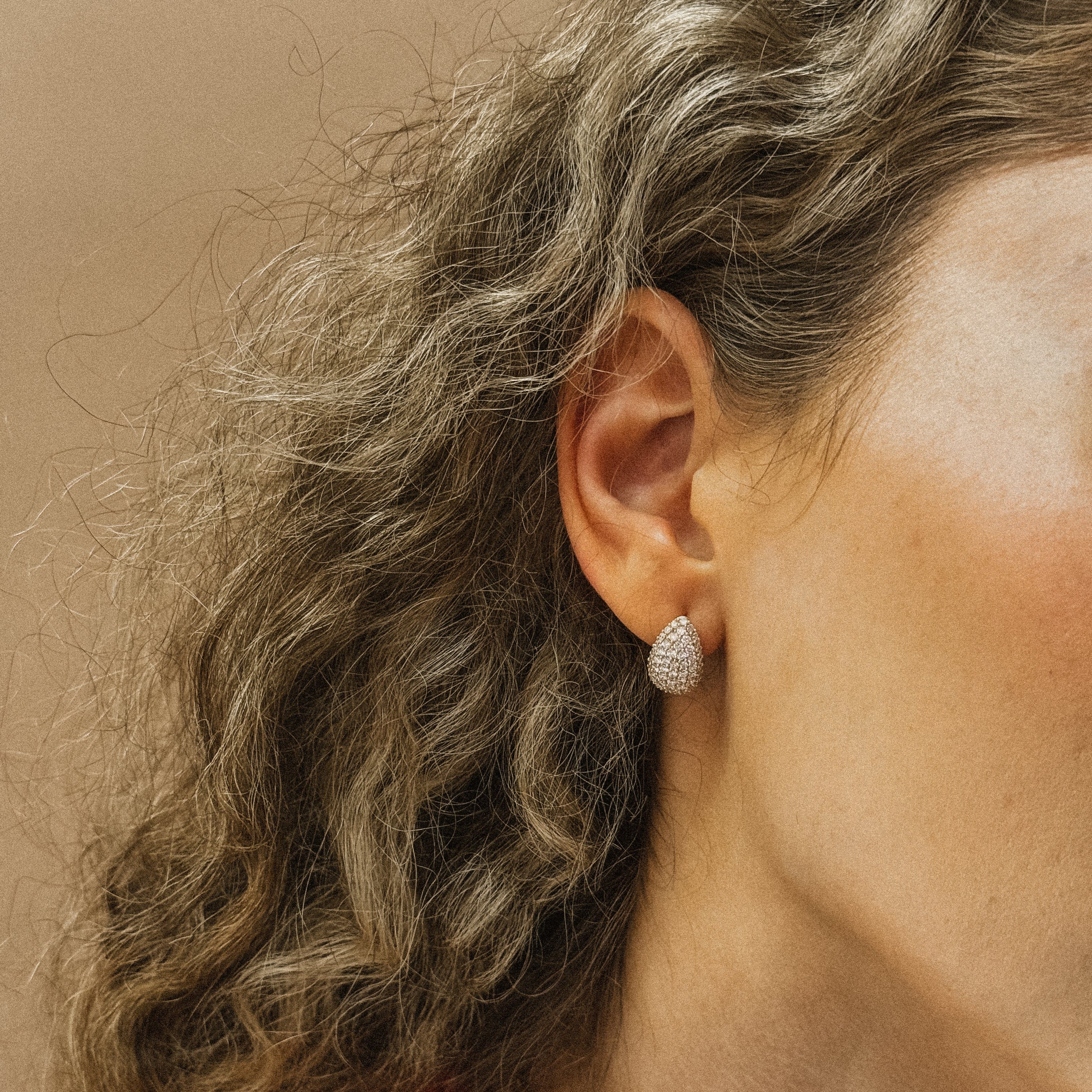 Close-up of a person's ear wearing a Diamond Teardrop Earrings with a red top.