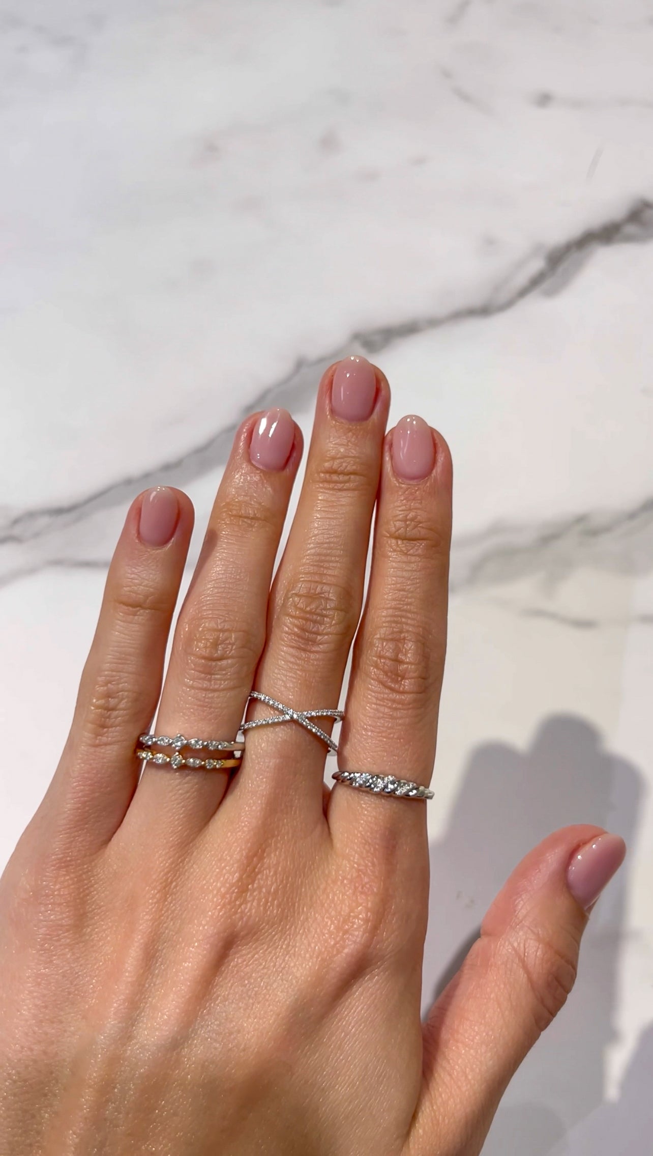 Double band diamond ring made with 14k white gold on a middle finger stacked with other rings