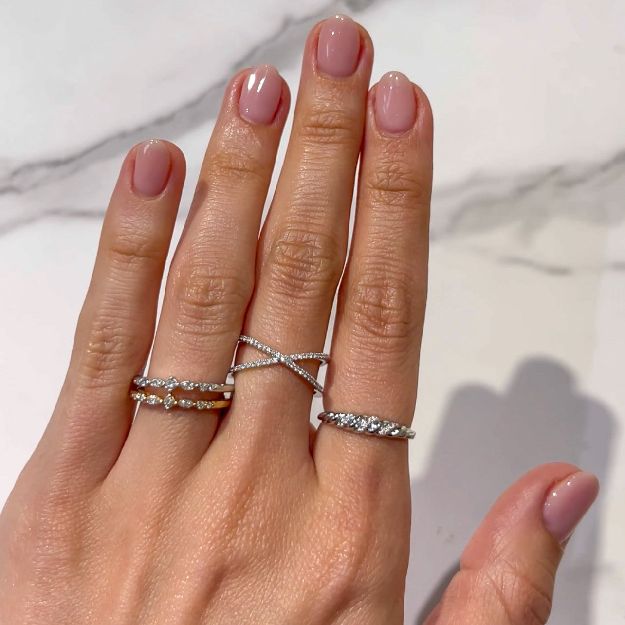 Double band diamond ring made with 14k white gold on a middle finger stacked with other rings