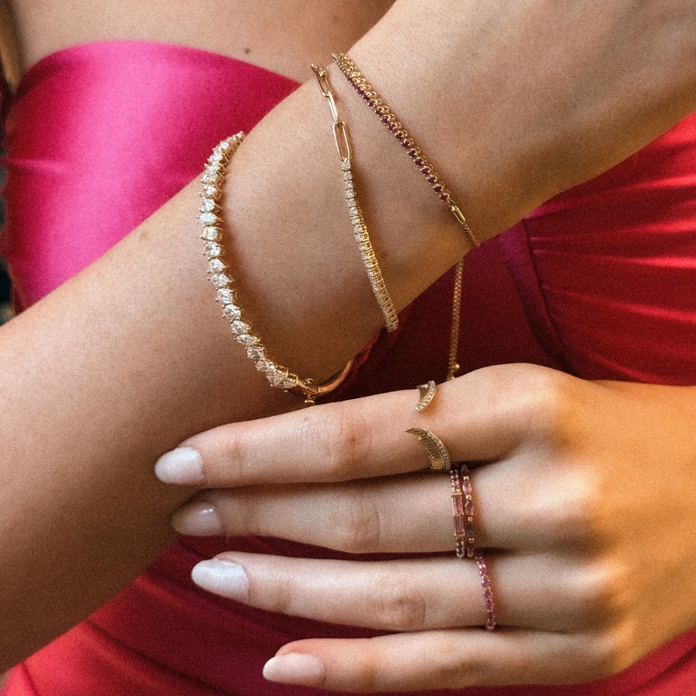Close-up of a person's arm and hand wearing gold bracelets and rings.