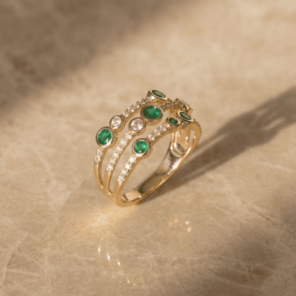 Gold ring with emeralds and diamonds on a beige surface