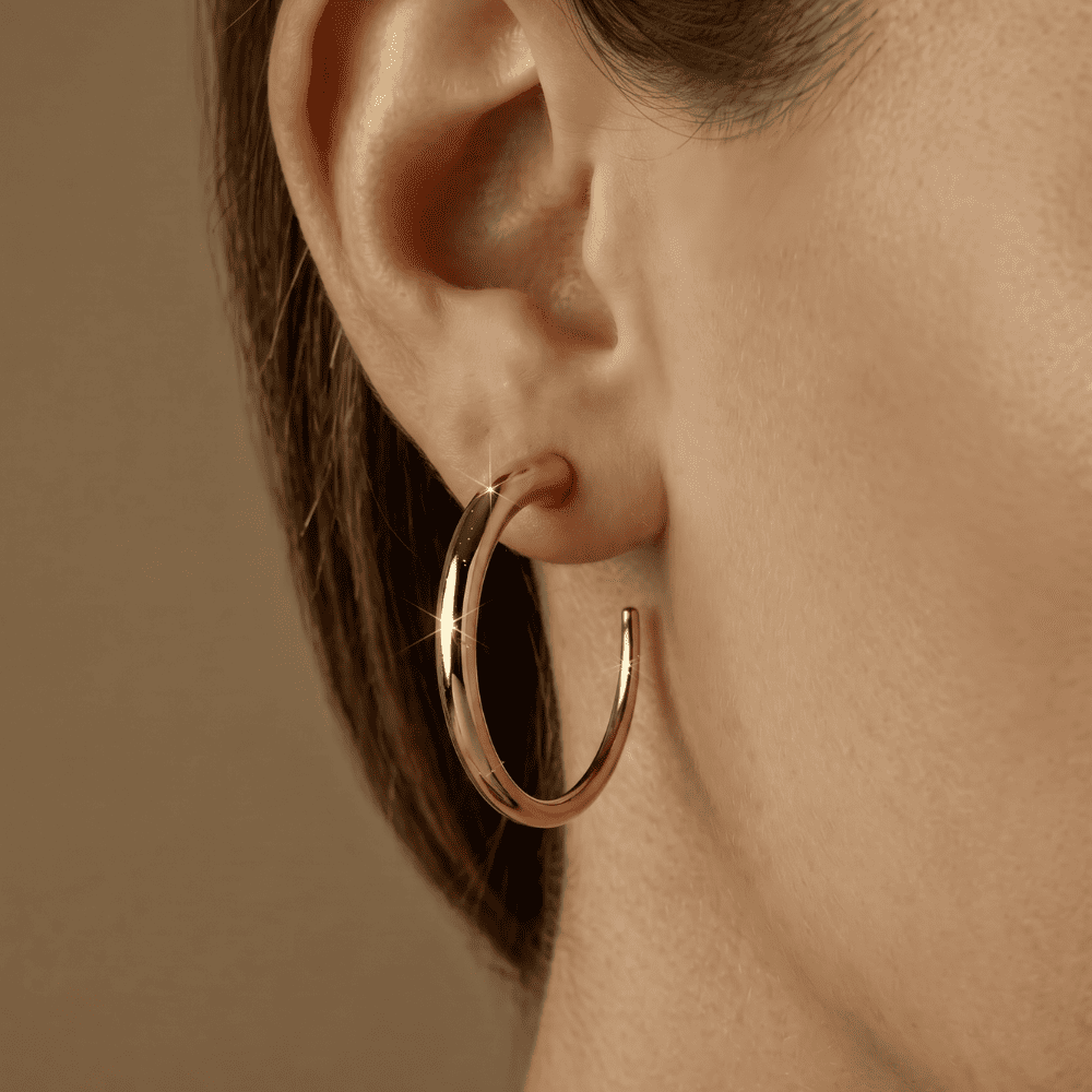 Close-up of a woman wearing a gold hoop earring against a beige background